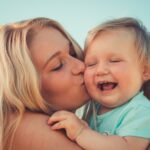 mother kissing baby daughter's cheek